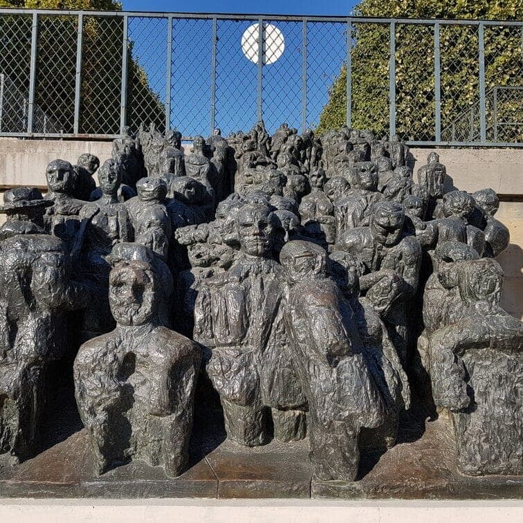 A bronze sculpture of a crowd of figures in a public park