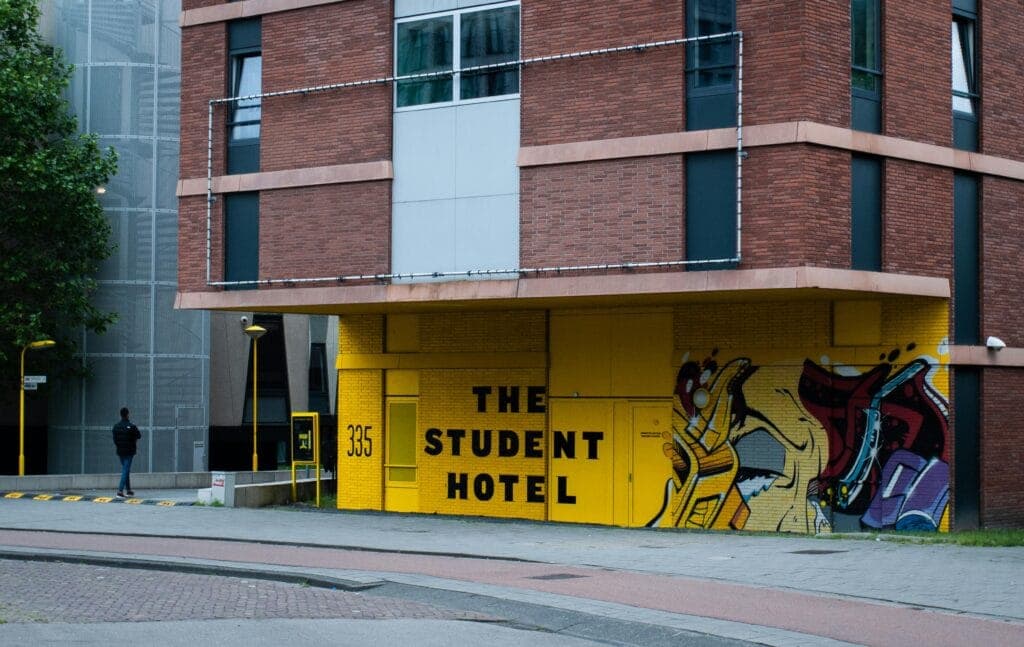 The entrance to The Student Hotel, with a mural on its yellow facade